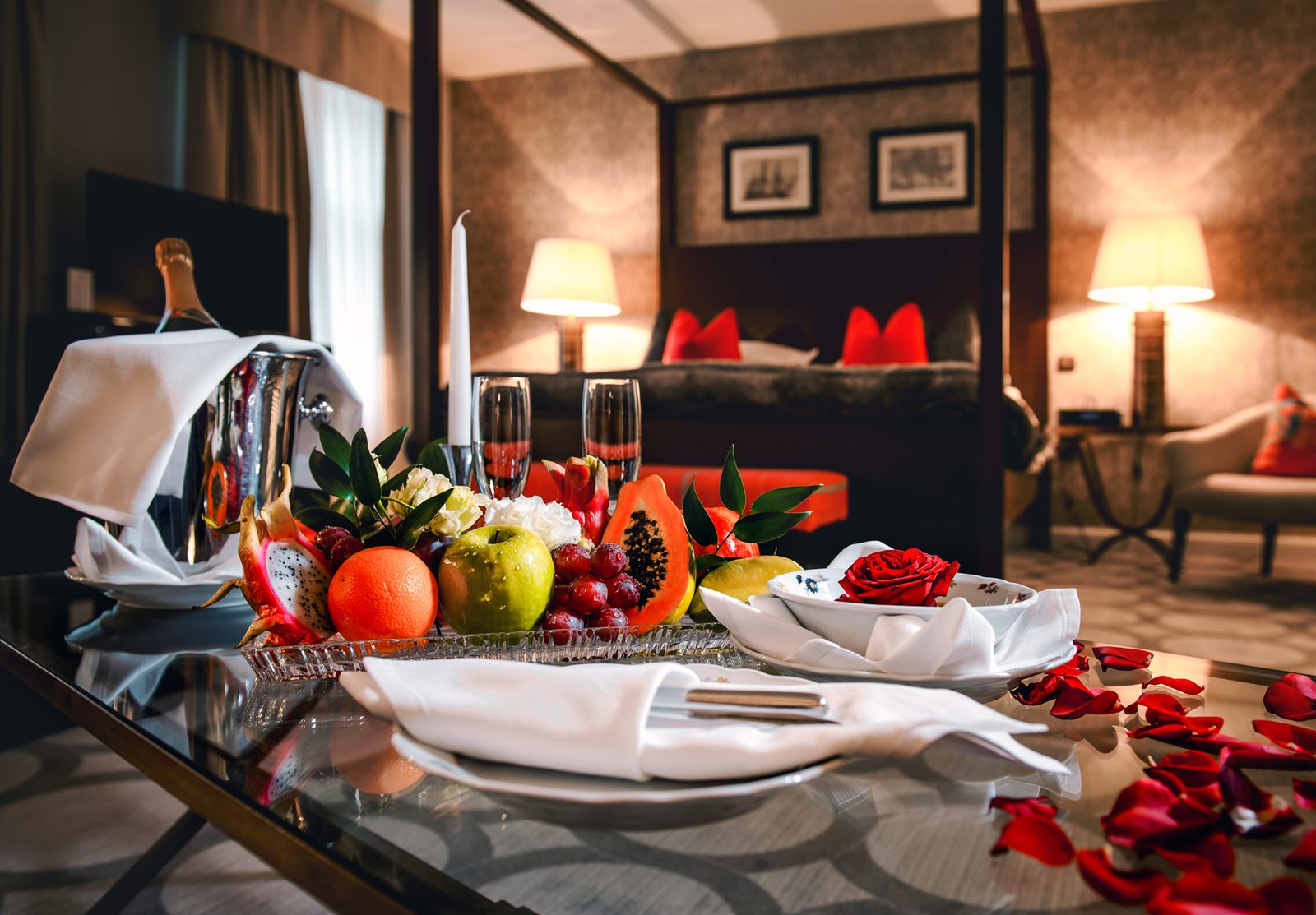 Champagne, fresh fruit and rose petals set out in a luxury suite